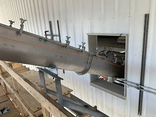 Inclined Screw Conveyor Projects Through Wall to Load Out Area